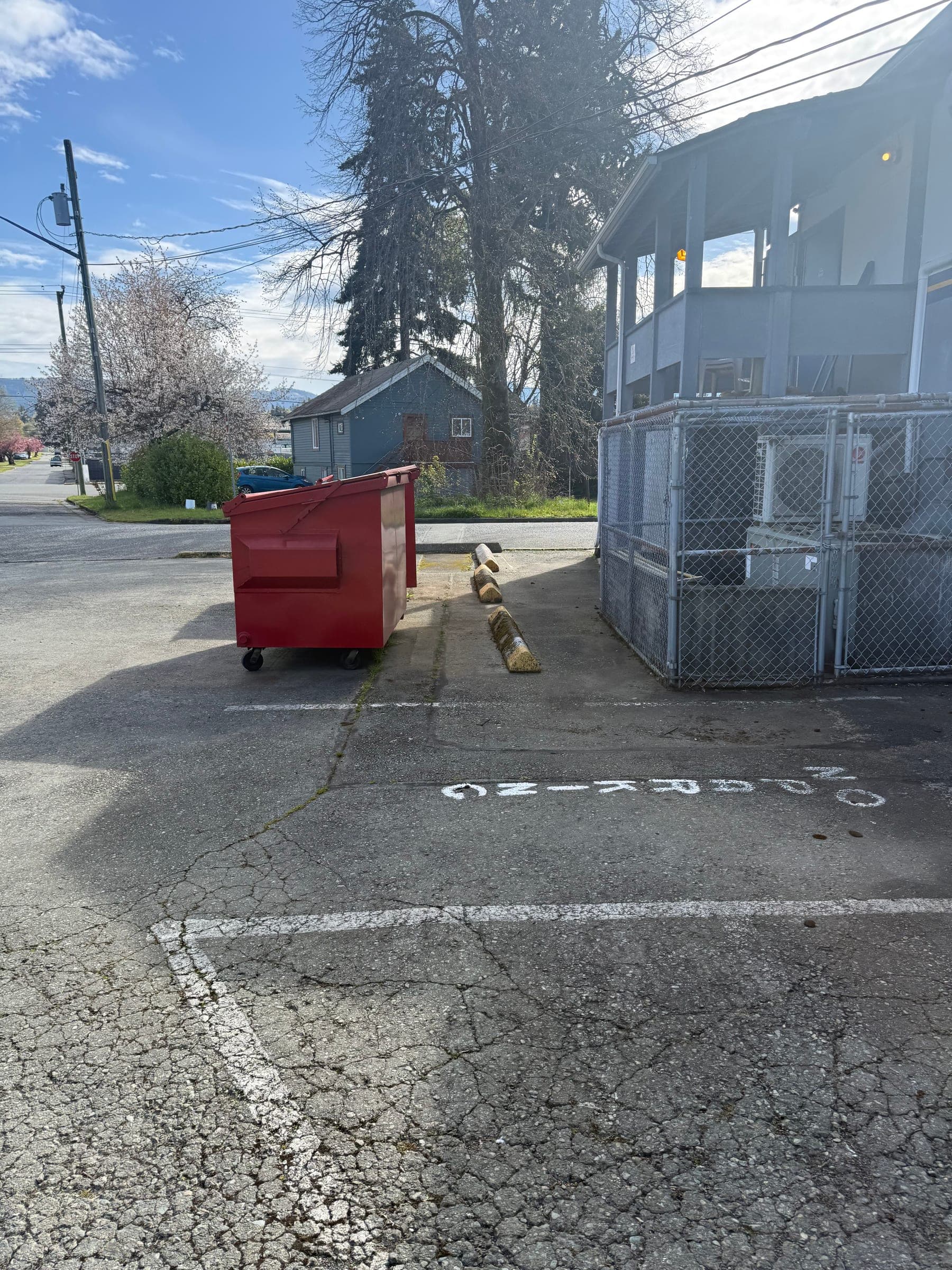 Before photo of cracked asphalt and worn curbside parking markings.