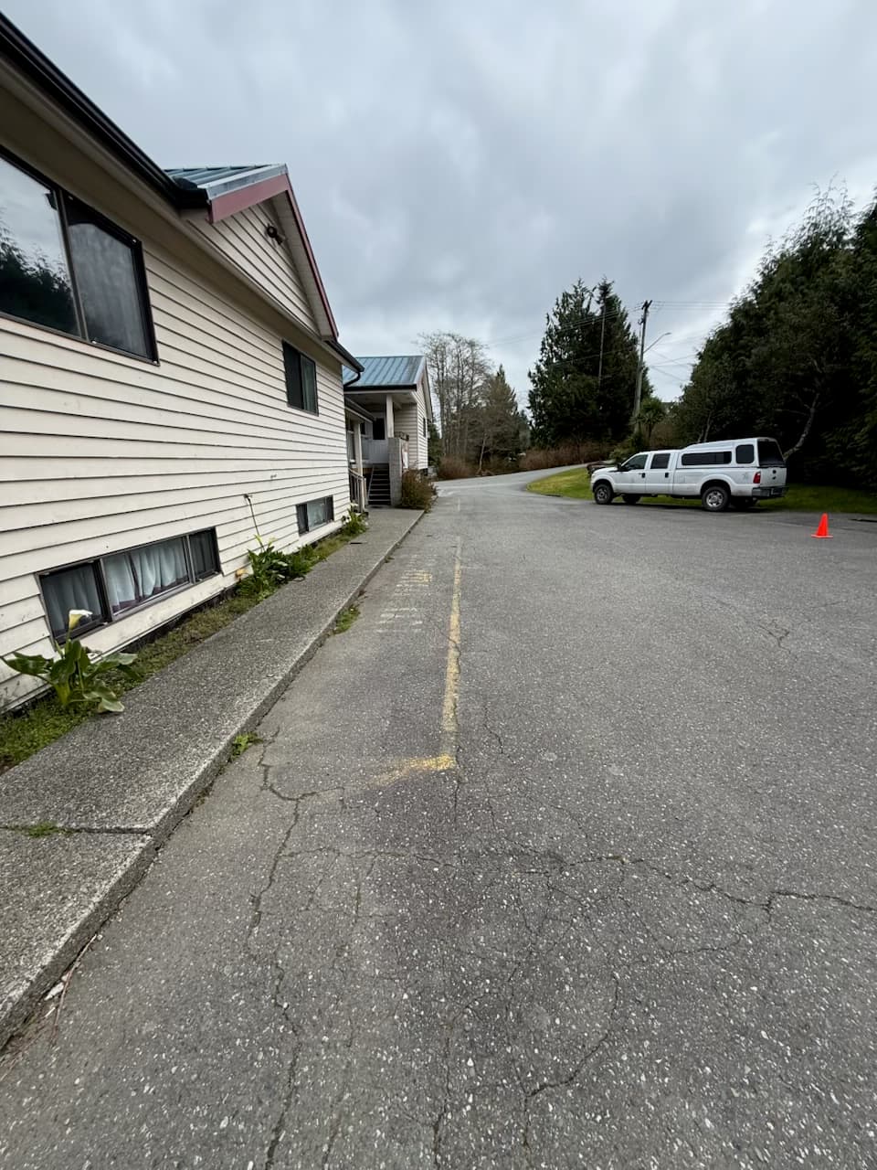 Before photo of faded parking stall lines beside a residential building.